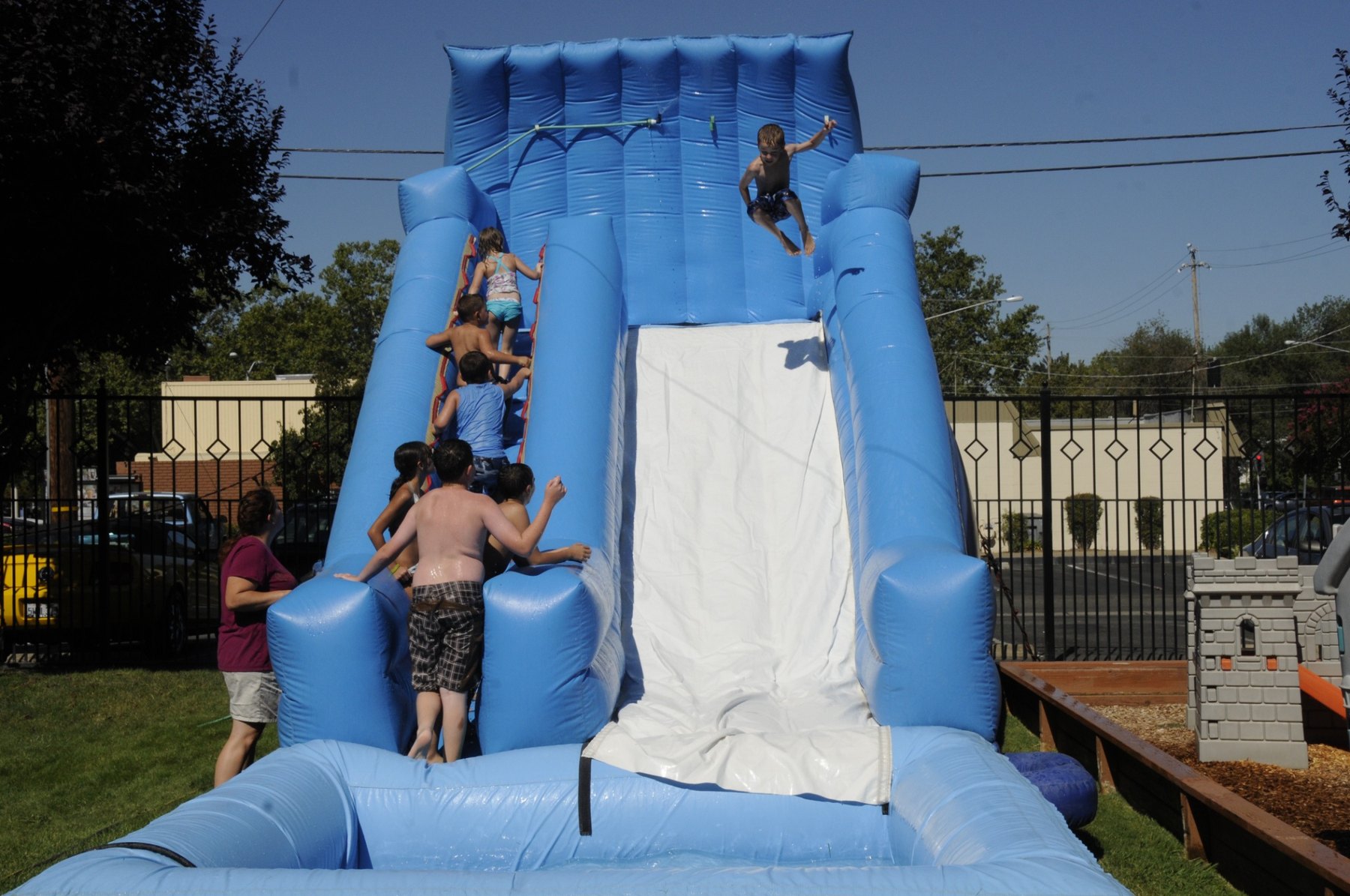 Children enjoying a large outdoor water slide at a church activity
