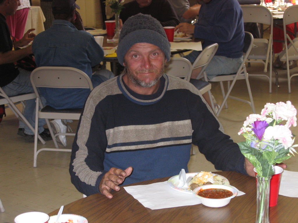 A man seated with a meal during a church community dinner.