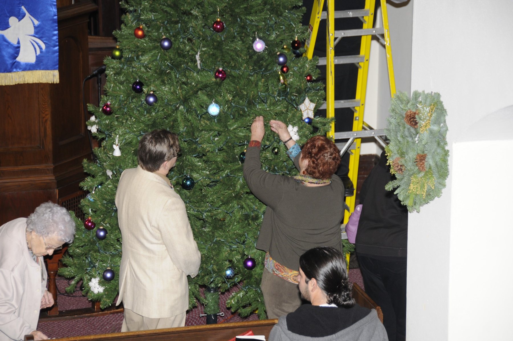 Church members adding ornaments and greenery for Christmas.
