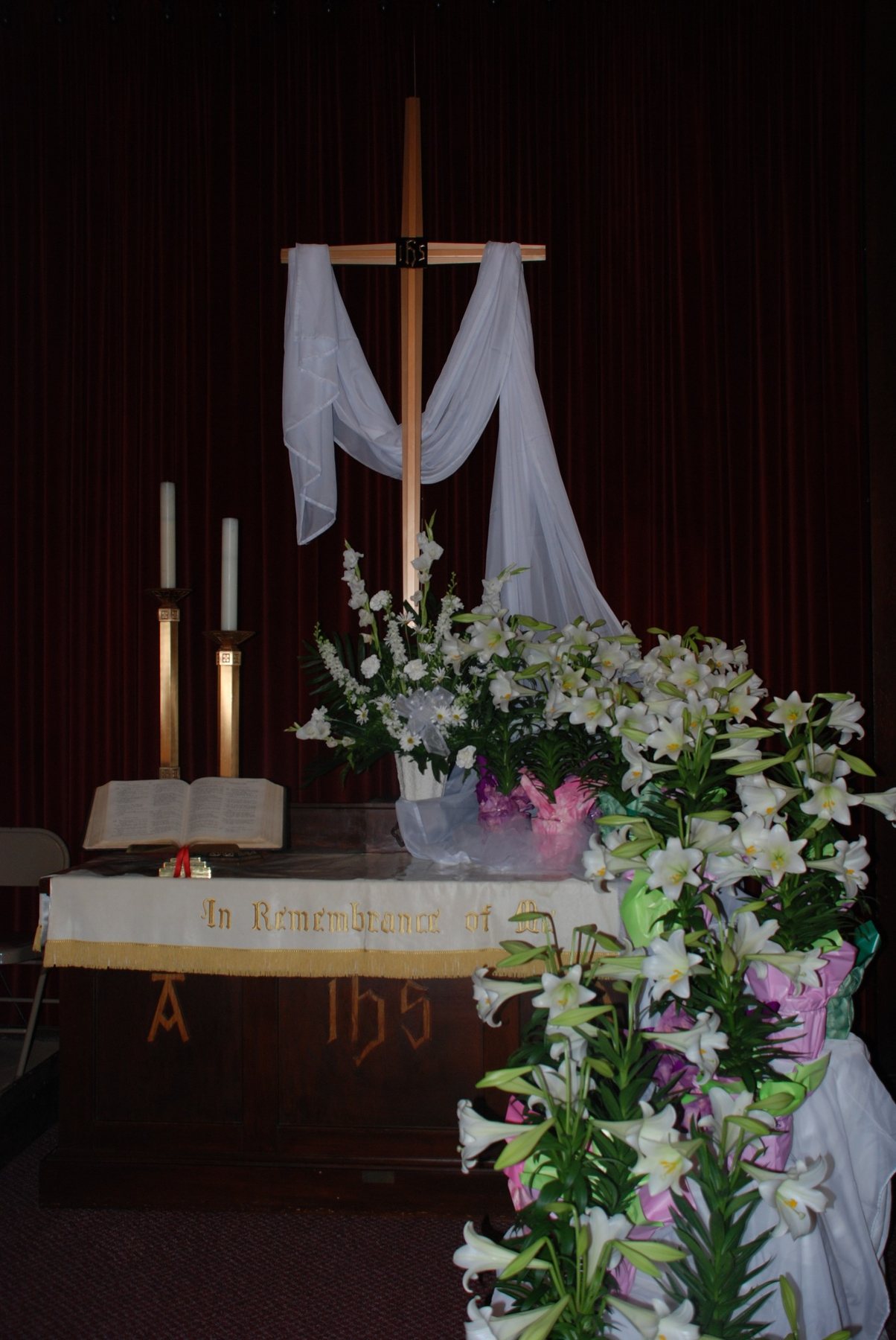 The Easter cross draped in white and surrounded by lilies.