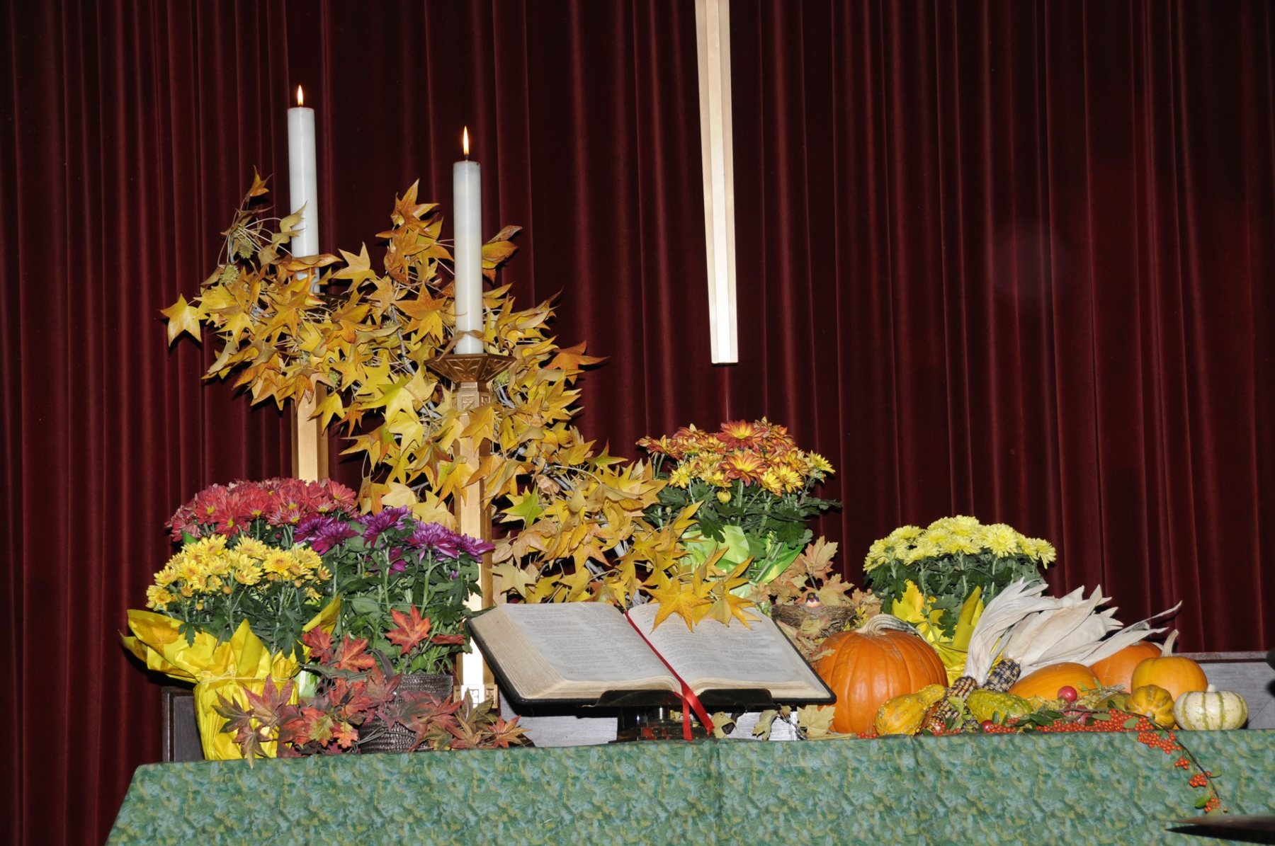 Autumn color, harvest gifts and an open Bible at the altar.