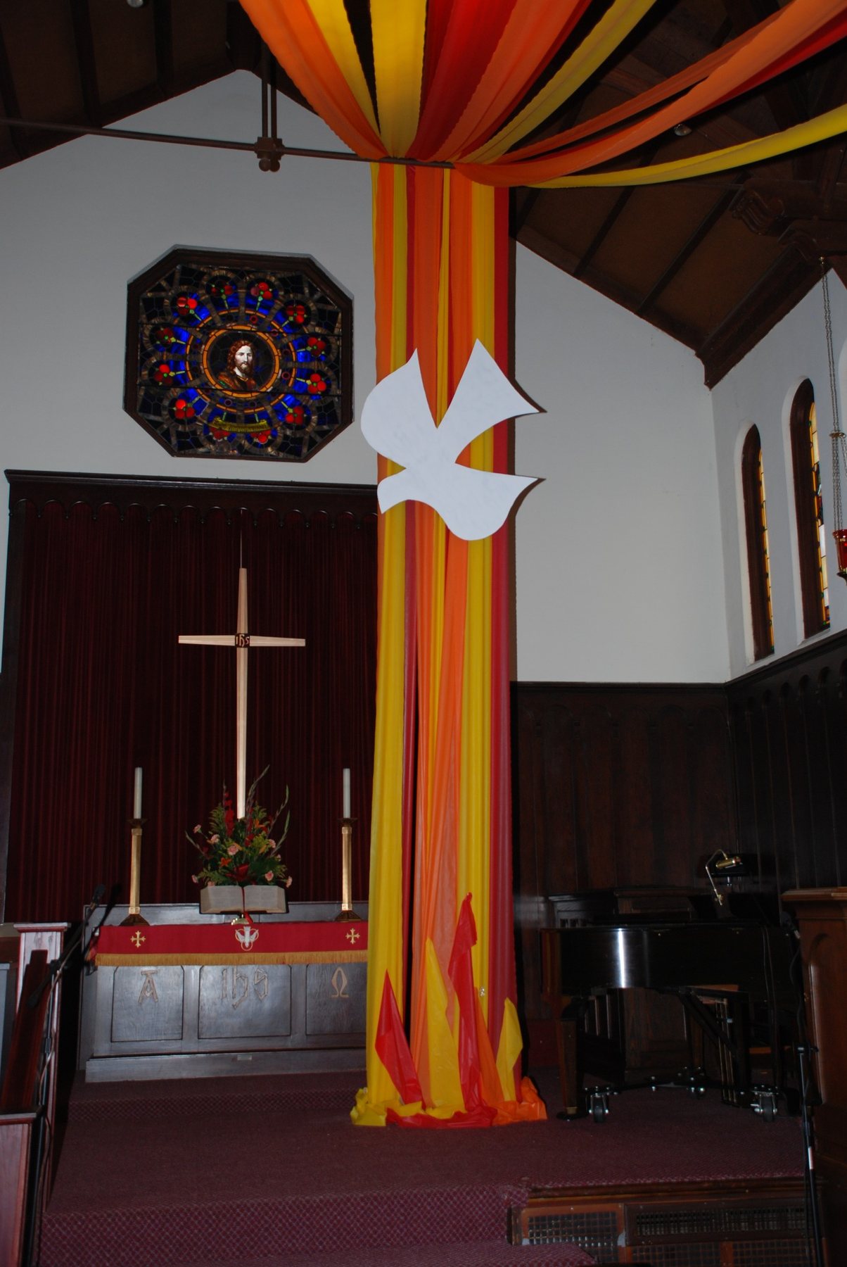 Pentecost color rises through the sanctuary beneath the dove.