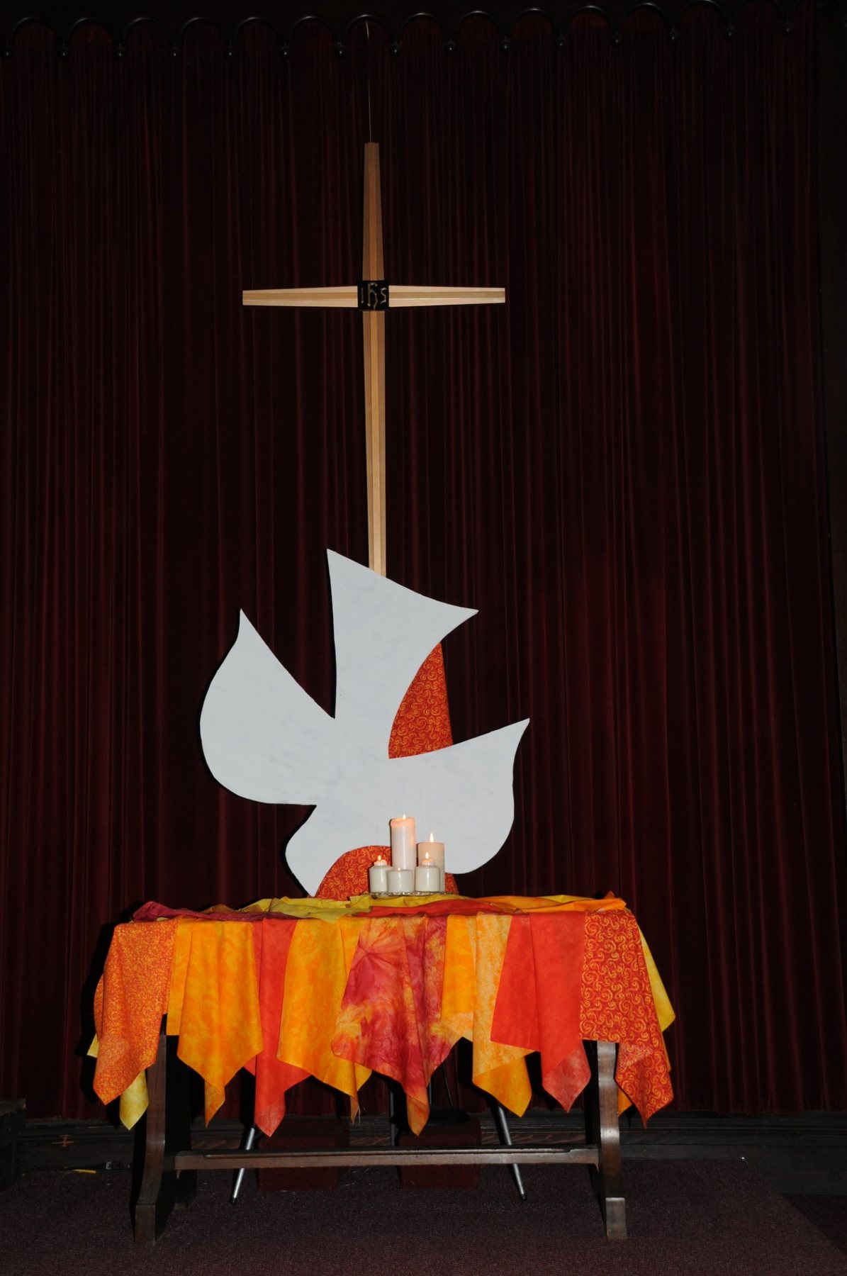 The dove, flame colors and candles evoke the Holy Spirit.